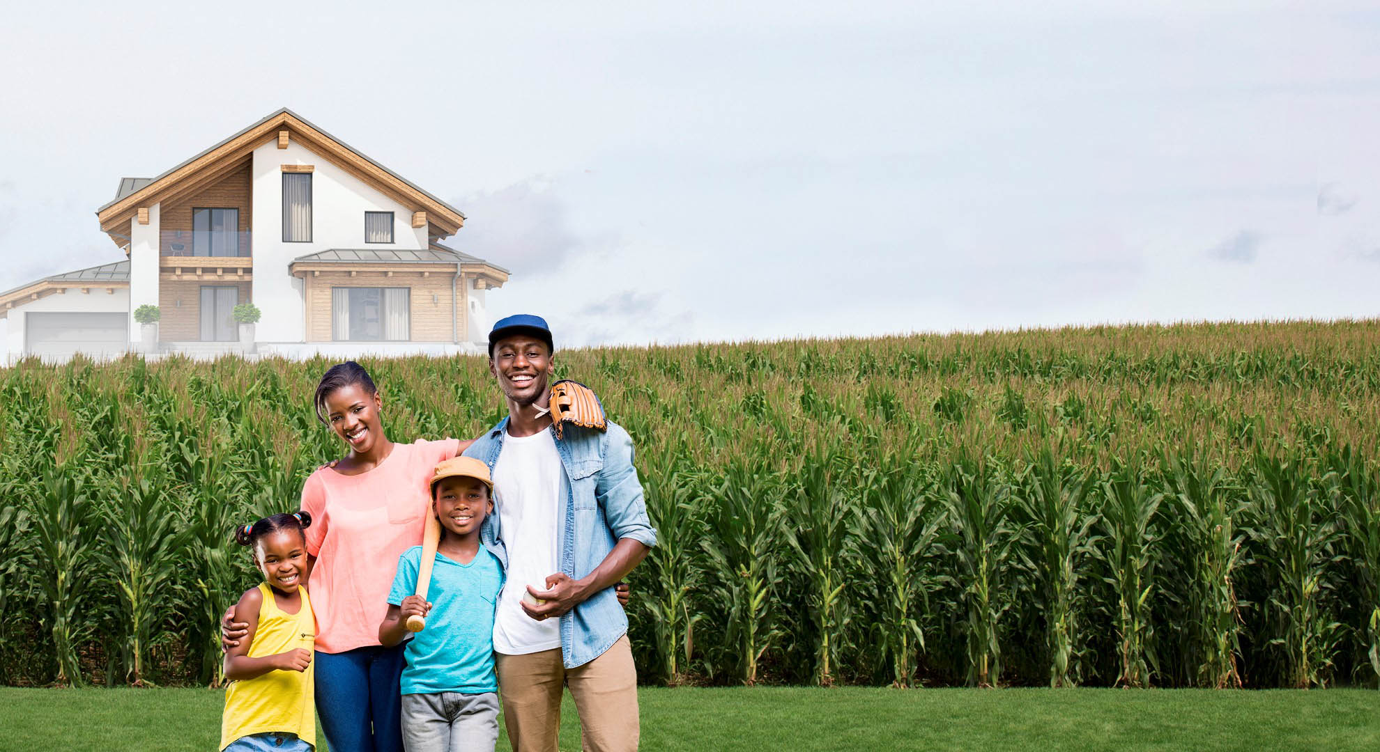 Family standing in corn field with baseball equipment with newly built home in the background